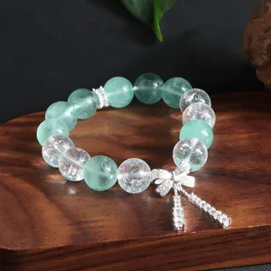 Nahaufnahme von grünem Fluorit- und Quarzkristallarmband mit funkelndem Schleife.