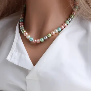 Détail d'un collier de perles de nacre multicolores sur un mannequin en chemise blanche