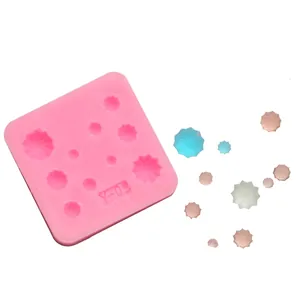 Detail view of a pink star-shaped silicone mold with colored resin samples