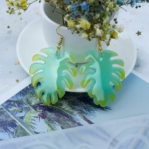 Gros plan de boucles d'oreilles Monstera en résine et moule en silicone assorti