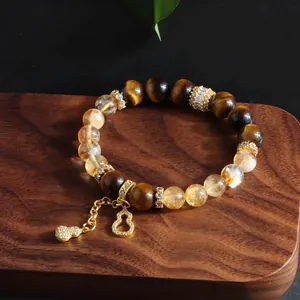 Detailed close-up of natural citrine and tiger's eye bracelet with golden gourd charm
