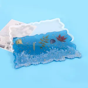 Macro view of an irregular wave silicone mold and finished blue resin coaster with gold flakes.