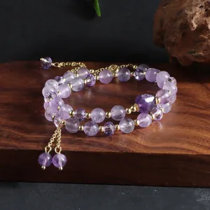 Macro view of a double-strand natural amethyst beaded bracelet with elegant gold tassels