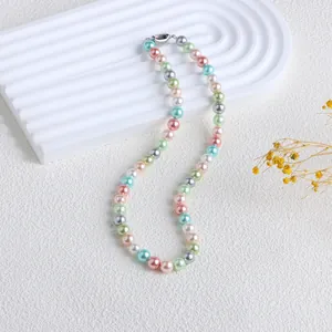 Vue détaillée d'un collier en perles de coquillage colorées sur un support ondulé blanc