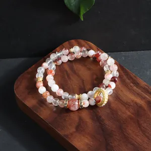Detailed close-up of a red flower crystal double-layer bracelet with a gold ring charm
