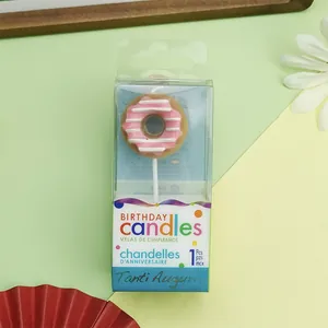 Detail view of a cute pink donut birthday candle in its transparent retail box packaging.