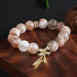 Detailansicht eines Naturkristall-Armbands mit goldenem Schleifenanhänger