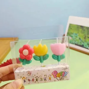 Nahaufnahme von drei bunten Geburtstagskerzen in Blumenform in niedlicher Partyverpackung