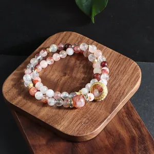 Detailed macro view of natural red flower crystal multi-layer bracelet on wooden stand.