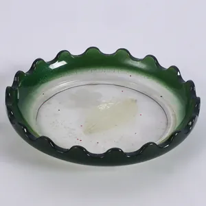 Vista dettagliata di un vassoio decorativo in resina verde con bordi ondulati e foglia.