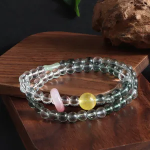 Detailed view of clear and green phantom crystal double-loop bracelet with pink ring.