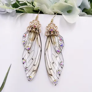 Nahaufnahme von eleganten Zikadenflügel-Ohrringen mit Strasssteinen und Goldakzenten