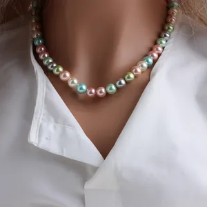 Détail d'un collier de perles de nacre multicolores sur un fond de chemise blanche