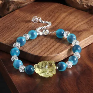 Nahaufnahme eines Perlenarmbands im chinesischen Stil mit blauem Achat und gelbem Anhänger.