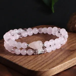 Gros plan d'un élégant bracelet double rang en quartz rose avec accents en cristal sur bois
