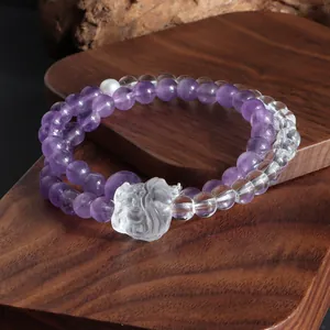 Détail d'un bracelet à double rang en améthyste et cristal de roche avec charme de lion.