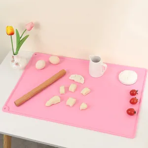 Pink thickened silicone kneading mat with raised edges used for rolling bread dough