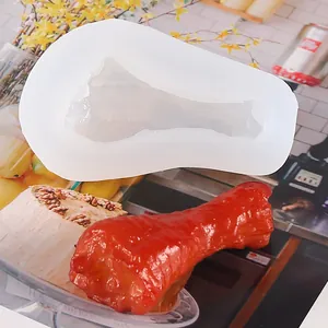 Detail showing the chicken drumstick silicone mold alongside a finished red resin sample piece.