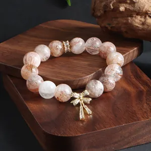 Nahaufnahme eines natürlichen Kristallarmbands mit goldenem Schleifenanhänger.