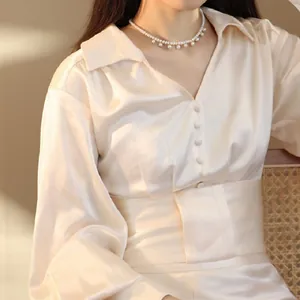 Detailansicht einer Naturperlenkette mit eleganten Anhängern am Hals eines Models