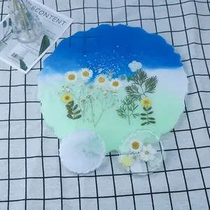 Macro di un vassoio artigianale in resina con sfumature blu e verdi e fiori essiccati.
