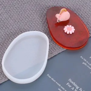 Molde de silicona blanco para posavasos junto a una pieza de resina ámbar acabada.