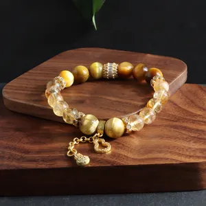 Close-up detail of tiger eye beads and gold hulu charm on stretch crystal bracelet