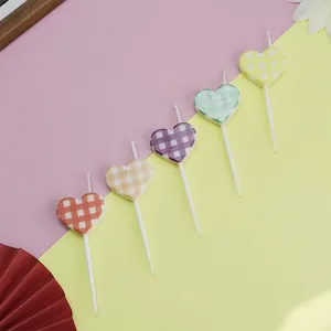 Detailed view of five colorful gingham heart-shaped birthday candles on a bright background