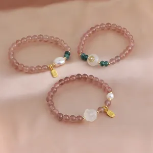 Detailed macro view of strawberry quartz crystal bracelets with pearls and gold Fu charms.