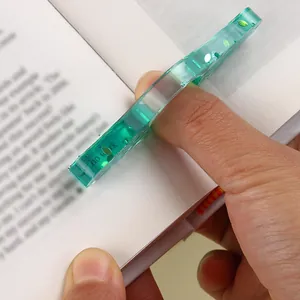Close-up of a green resin thumb book holder being used to hold pages open.