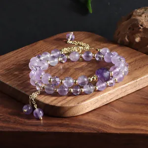 Close-up detail of a double-layered amethyst beaded bracelet with gold spacers and tassel