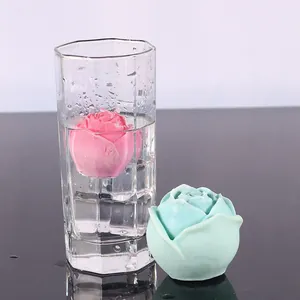 Detalle de una bola de hielo en forma de rosa flotando en un vaso y colocada sobre una mesa