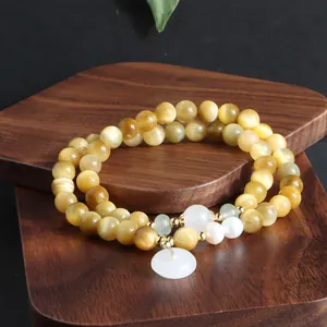 Detaillierte Ansicht eines goldenen Tigerauge-Armbands mit Perlen und weißem Anhänger.