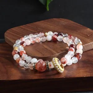 Close-up of a double-layered natural red lepidocrocite quartz bead bracelet with gold charms