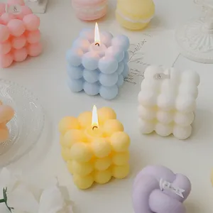 Colección estética de velas aromáticas de cubos de burbujas pastel en una mesa blanca