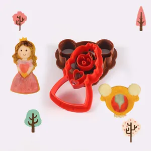 Detalle de cortadores de galletas de plástico rojo y marrón con galletas de princesa