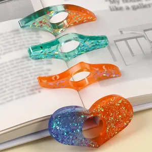Close-up of sparkling resin thumb book page holders in various colors and shapes
