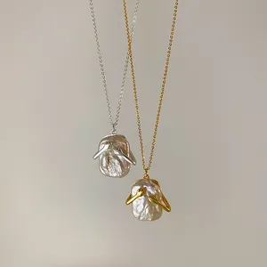 Primo piano di ciondoli con perle barocche e design a braccia avvolgenti in oro e argento.