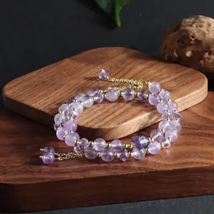 Macro view of a double-strand natural purple amethyst bracelet featuring a delicate golden tassel