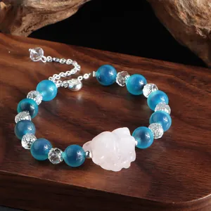 Nahaufnahme der rosa Achat-Katze auf einem blauen Kristallperlenarmband mit Holzgrund