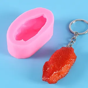 Detailed view showing a pink silicone mold and the finished realistic chicken wing keychain.