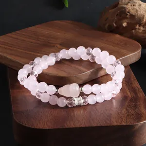 Gros plan d'un bracelet double rang en quartz rose avec pendentif renard sur bois.