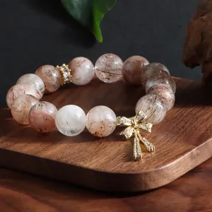 Elegantes Naturkristall-Armband mit einem funkelnden goldenen Schleifenanhänger