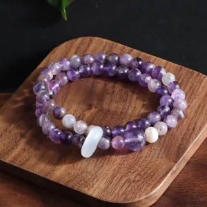 Close-up of a double-strand natural amethyst bracelet with white decorative beads on wood