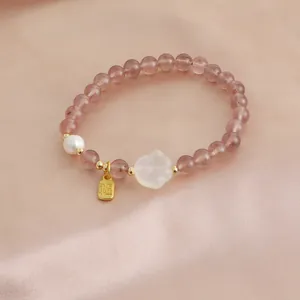 Detailed close-up of natural strawberry quartz bracelet with pearl and cat paw charm