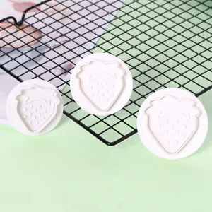 Driedelige set witte aardbeivormige koekjesuitstekers met een veerdrukmechanisme.