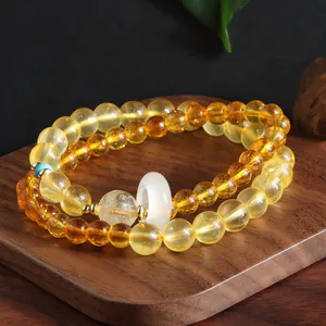 Close-up of double-strand citrine bracelet with white jade ring on wooden board