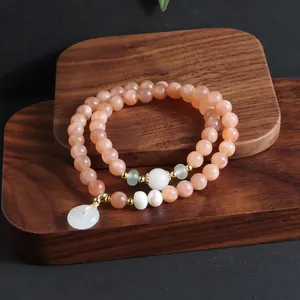 Detailaufnahme eines Sonnenstein-Armbands mit weißem Jade-Anhänger im neuen chinesischen Stil.