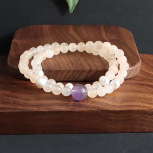 Detailweergave van een dubbele armband met roze kristallen, parels en een paarse amethist.