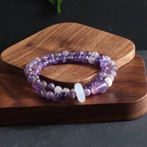 Close-up of a multi-layer natural amethyst beaded bracelet with a white pearl and jade ring.